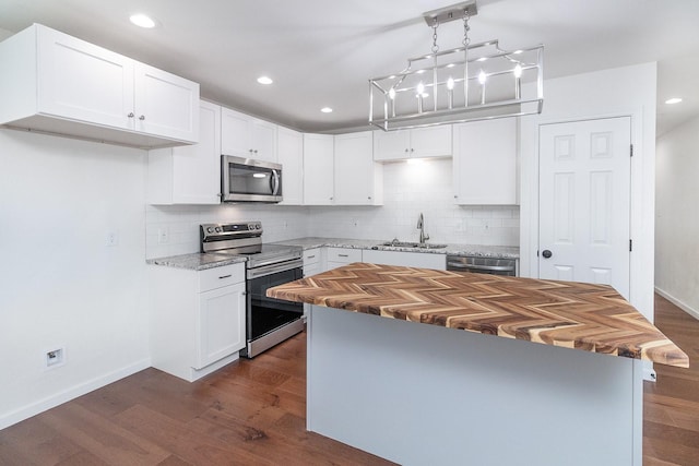 kitchen featuring stainless steel appliances, a kitchen island, white cabinets, and sink