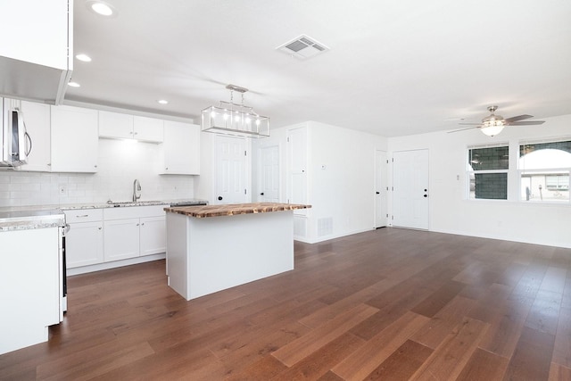 kitchen with pendant lighting, dark hardwood / wood-style flooring, a kitchen island, sink, and white cabinetry