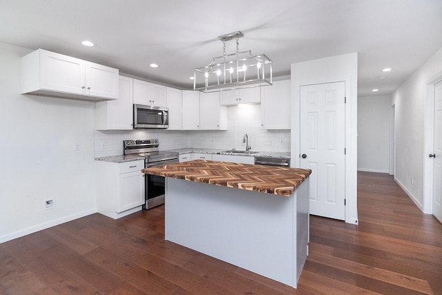 kitchen featuring dark wood-type flooring, a kitchen island, white cabinets, appliances with stainless steel finishes, and sink