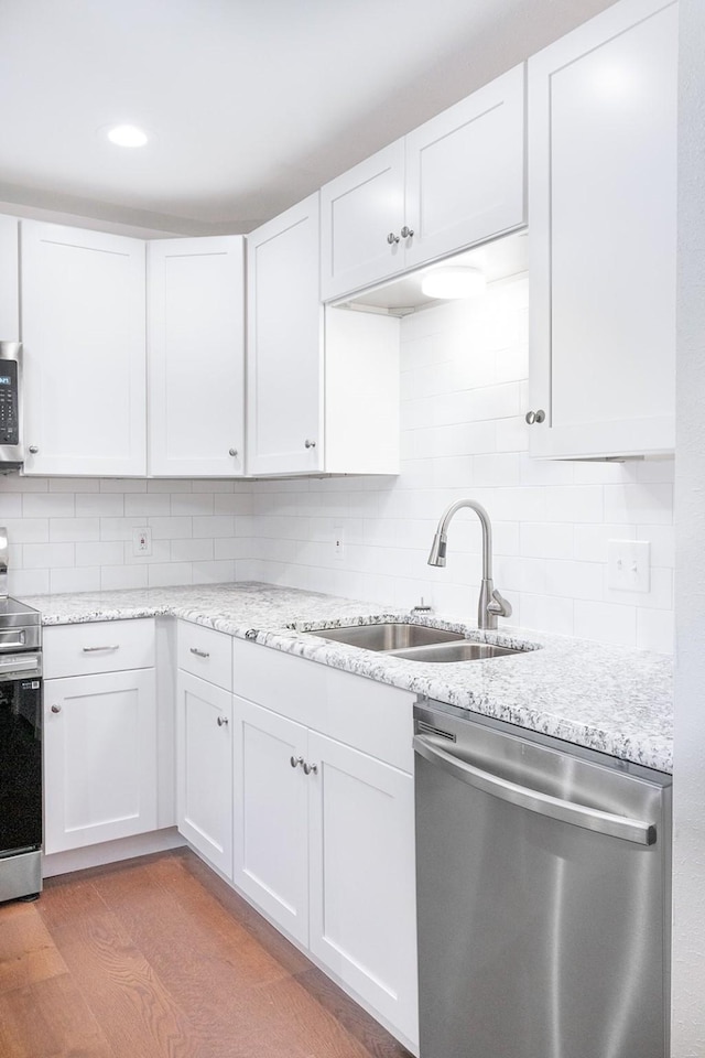 kitchen with sink, stainless steel appliances, tasteful backsplash, and white cabinetry