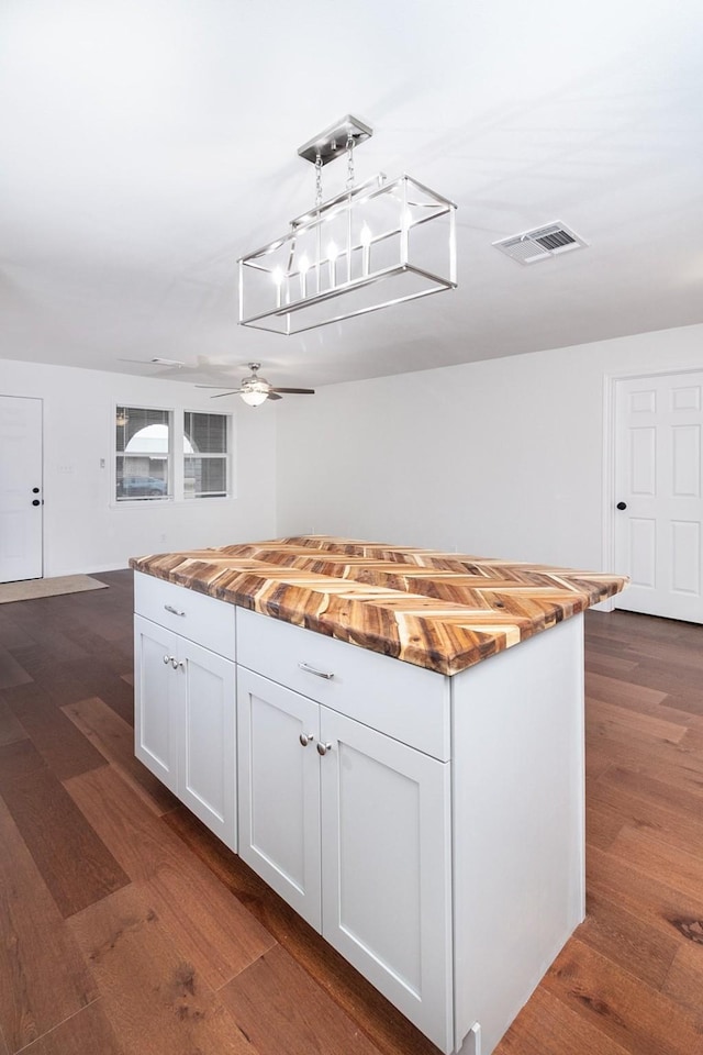 kitchen featuring wooden counters, white cabinets, decorative light fixtures, and dark hardwood / wood-style flooring