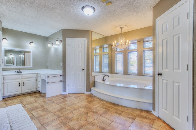 bathroom with a textured ceiling, tile patterned floors, a tub to relax in, vanity, and a notable chandelier