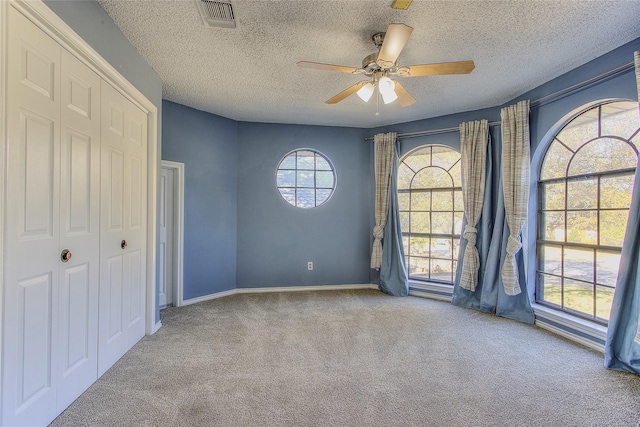 unfurnished bedroom featuring light colored carpet, ceiling fan, and a textured ceiling