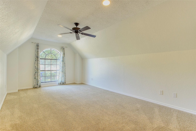 additional living space with lofted ceiling, a textured ceiling, ceiling fan, and light carpet