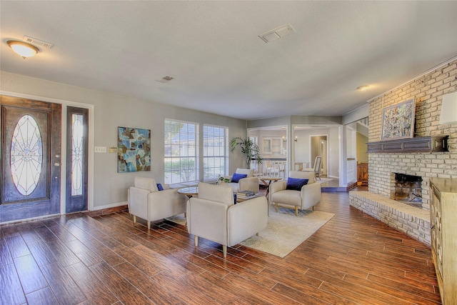 living room featuring a textured ceiling, a brick fireplace, and dark hardwood / wood-style floors