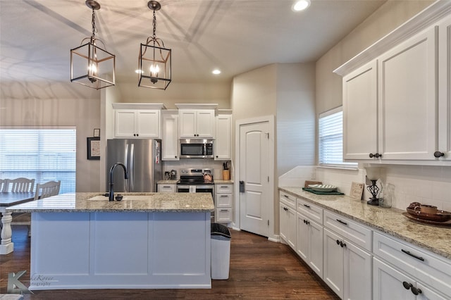 kitchen with dark wood-type flooring, pendant lighting, a kitchen island with sink, white cabinetry, and appliances with stainless steel finishes