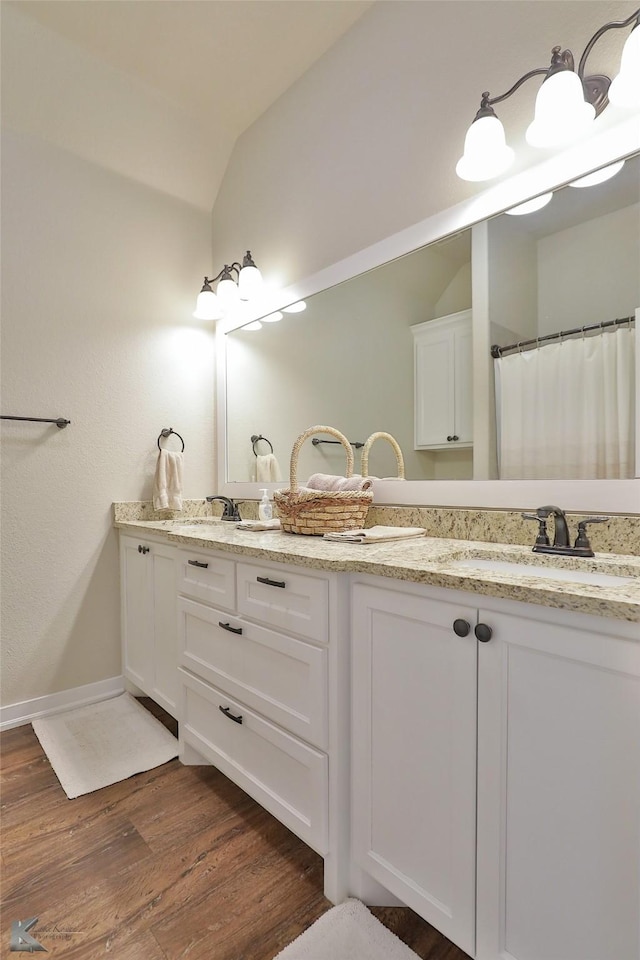 bathroom with hardwood / wood-style floors, vaulted ceiling, and vanity