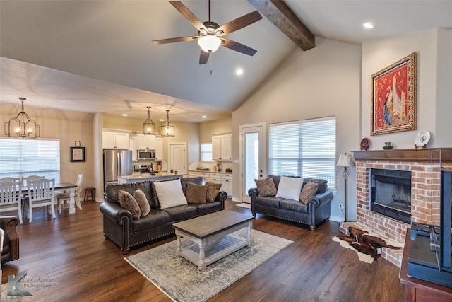 living room featuring ceiling fan with notable chandelier, a brick fireplace, dark hardwood / wood-style flooring, and beamed ceiling