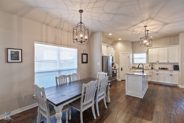 dining area featuring dark wood-type flooring, an inviting chandelier, and sink