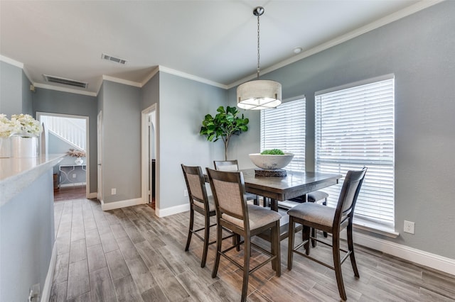 dining room featuring a healthy amount of sunlight, ornamental molding, and wood-type flooring