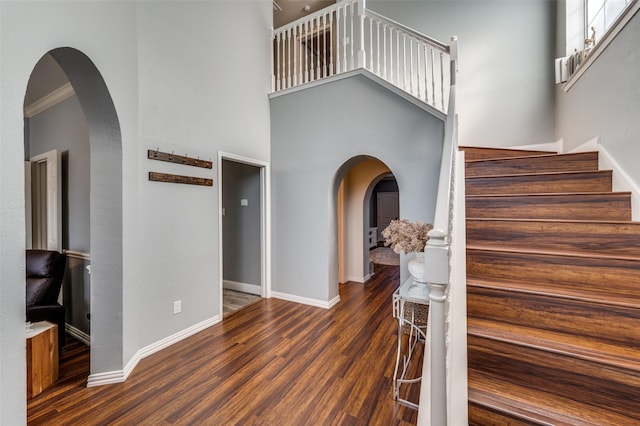 entrance foyer with a towering ceiling, ornamental molding, and dark hardwood / wood-style floors