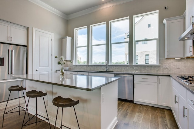 kitchen with a center island, stainless steel appliances, a kitchen bar, white cabinetry, and sink