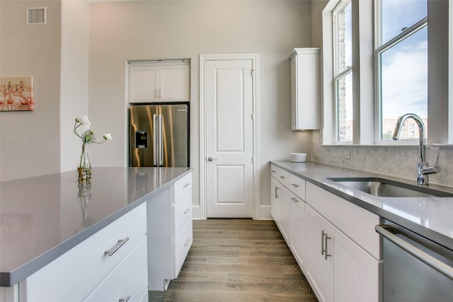 kitchen featuring appliances with stainless steel finishes, a healthy amount of sunlight, white cabinets, and sink