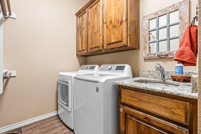 clothes washing area with sink, cabinets, and washer and clothes dryer