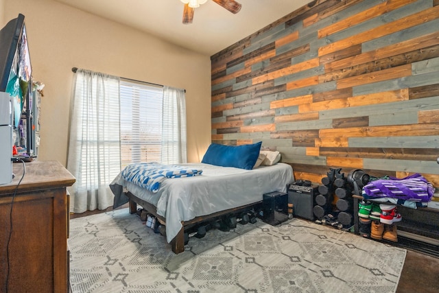 bedroom featuring ceiling fan and wooden walls