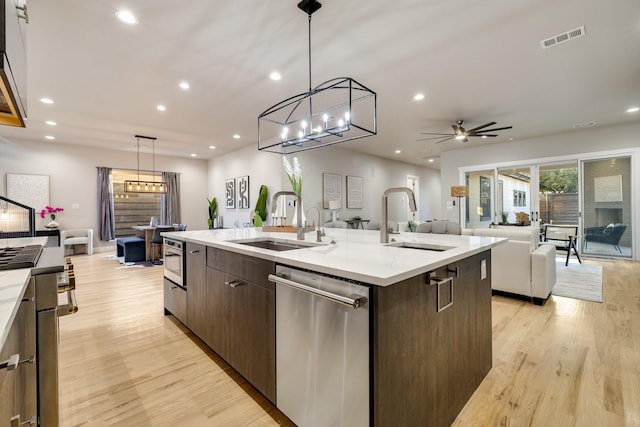 kitchen with a spacious island, stainless steel dishwasher, sink, and hanging light fixtures