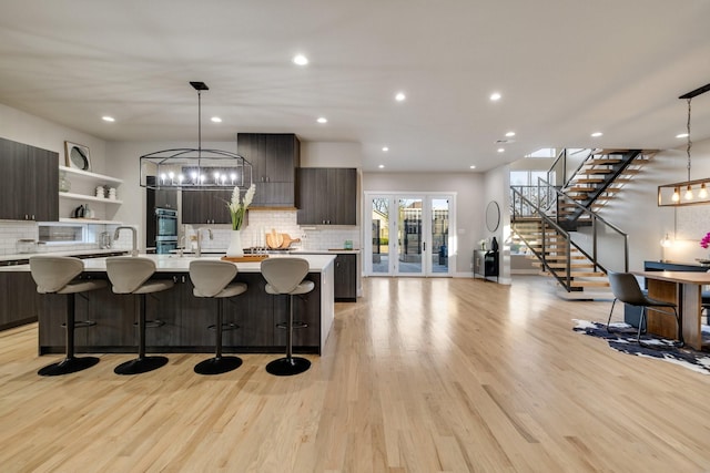 kitchen with pendant lighting, dark brown cabinets, an island with sink, and a breakfast bar