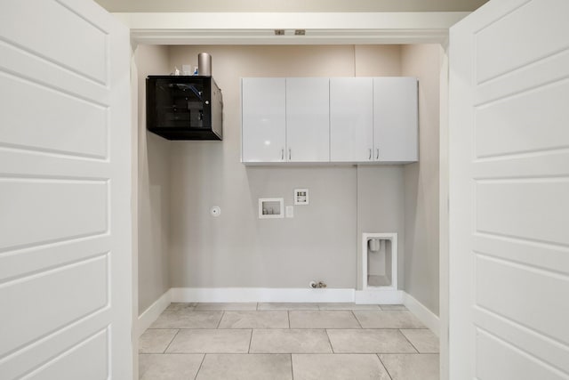 laundry area featuring gas dryer hookup, washer hookup, light tile patterned floors, and cabinets