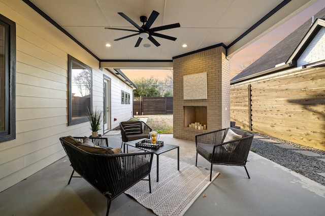 patio terrace at dusk featuring ceiling fan and an outdoor living space with a fireplace