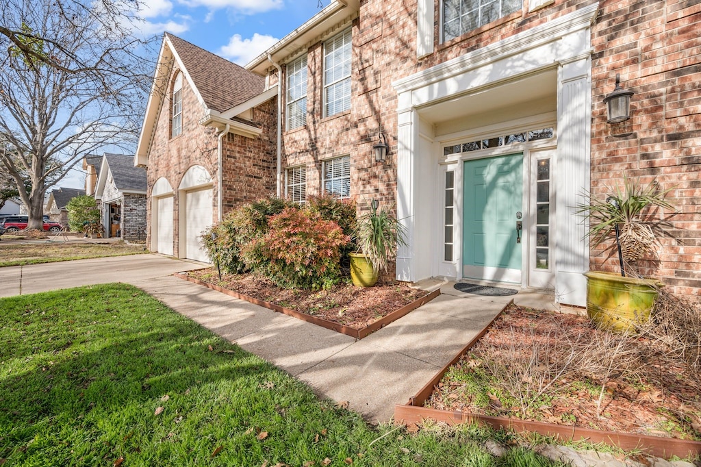 property entrance featuring concrete driveway and brick siding