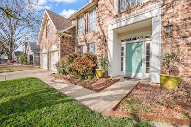 property entrance featuring concrete driveway and brick siding