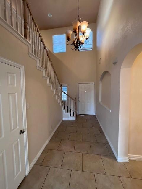 tiled entrance foyer featuring a high ceiling and a chandelier