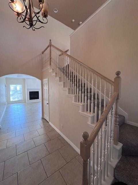 staircase with a notable chandelier, tile patterned flooring, and a towering ceiling