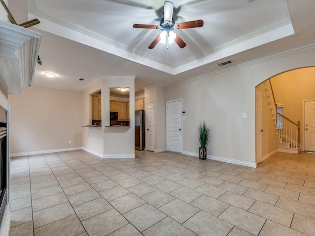 unfurnished living room featuring a raised ceiling, crown molding, light tile patterned flooring, and ceiling fan