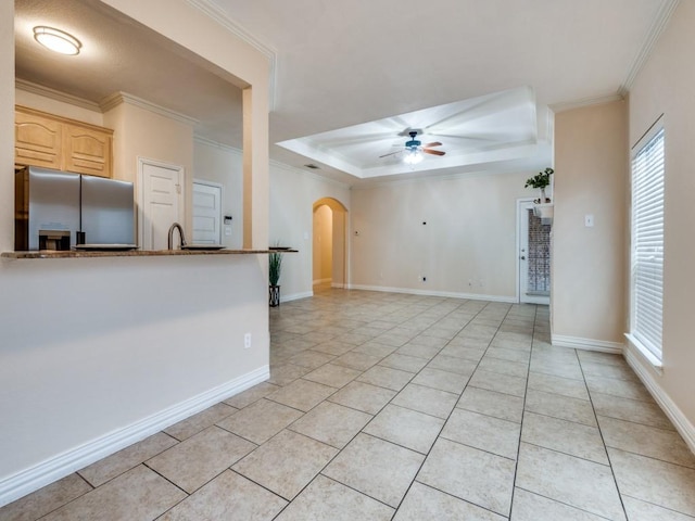 unfurnished living room featuring sink, crown molding, ceiling fan, light tile patterned flooring, and a raised ceiling