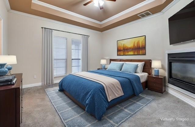 carpeted bedroom featuring crown molding, a raised ceiling, and ceiling fan