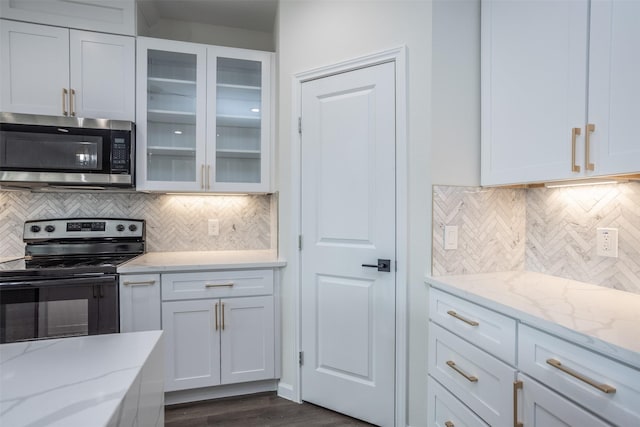 kitchen with light stone countertops, white cabinets, backsplash, and range with electric cooktop