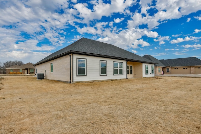 back of property featuring central AC unit and a yard