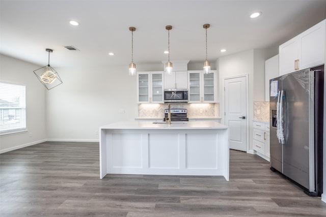 kitchen featuring hanging light fixtures, white cabinets, appliances with stainless steel finishes, and a center island with sink