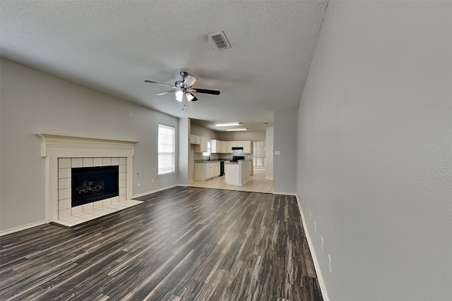 unfurnished living room featuring a textured ceiling, ceiling fan, a tile fireplace, and hardwood / wood-style flooring