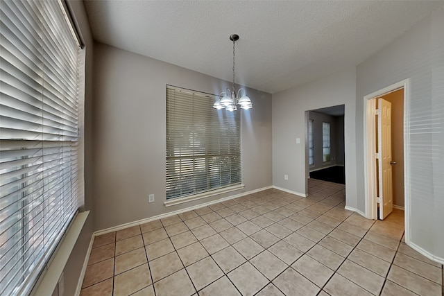 unfurnished dining area with a textured ceiling, a chandelier, and light tile patterned floors