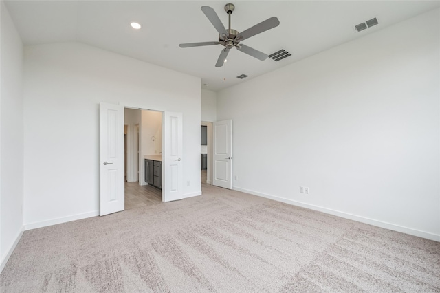 unfurnished bedroom with ceiling fan, light carpet, vaulted ceiling, and ensuite bath