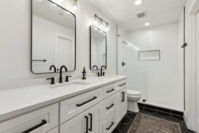 bathroom featuring toilet, tile patterned flooring, tiled shower, and vanity