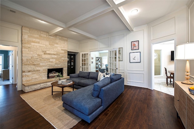 living room with beam ceiling, crown molding, dark hardwood / wood-style flooring, coffered ceiling, and a stone fireplace