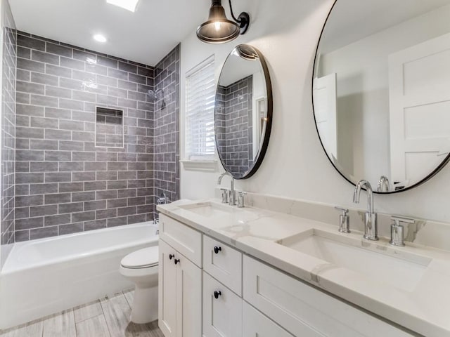 full bathroom featuring vanity, tiled shower / bath combo, and toilet