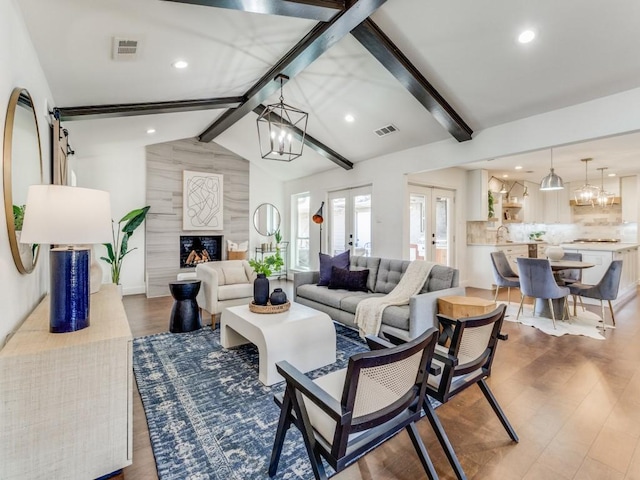 living room featuring vaulted ceiling with beams, french doors, hardwood / wood-style flooring, a high end fireplace, and a chandelier