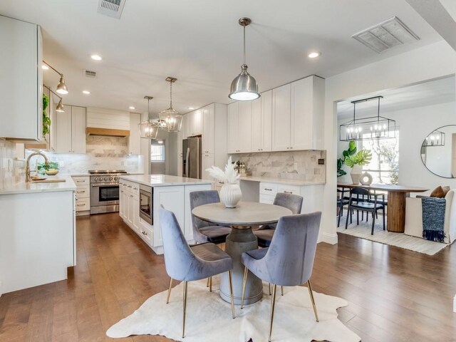 kitchen with backsplash, stainless steel appliances, white cabinets, and a center island