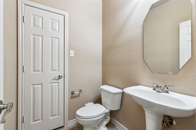 bathroom with toilet, tile patterned flooring, and sink