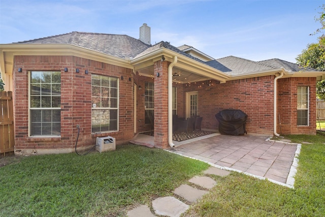 rear view of house with a lawn and a patio