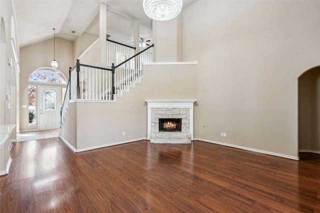 unfurnished living room featuring high vaulted ceiling, hardwood / wood-style floors, ceiling fan, and a stone fireplace