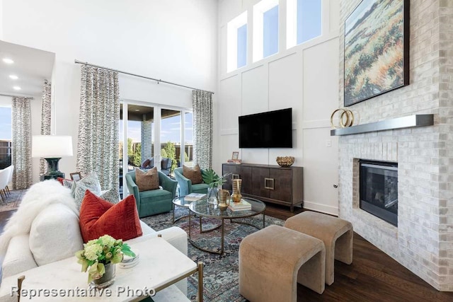 living room featuring a high ceiling, a brick fireplace, and wood-type flooring