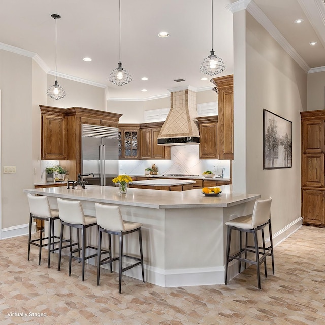 kitchen with stainless steel appliances, a large island with sink, premium range hood, a kitchen bar, and decorative light fixtures