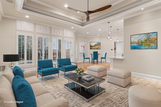 living room with ceiling fan, a raised ceiling, and crown molding