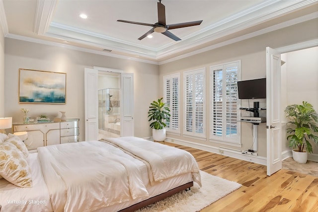 bedroom with connected bathroom, crown molding, ceiling fan, a tray ceiling, and light hardwood / wood-style flooring