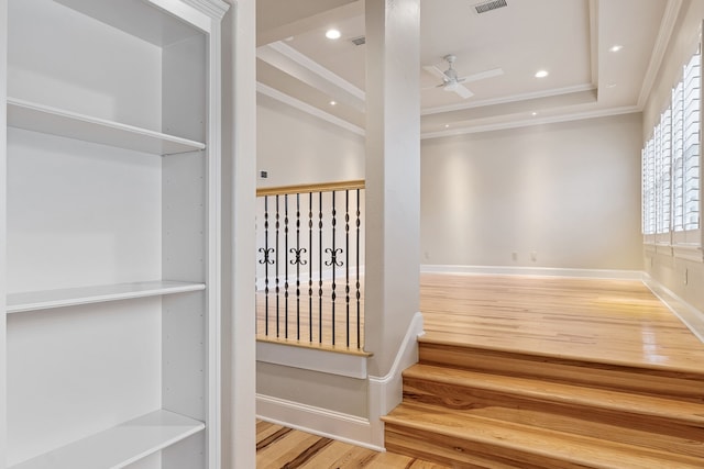 interior space with a raised ceiling, ceiling fan, and hardwood / wood-style flooring