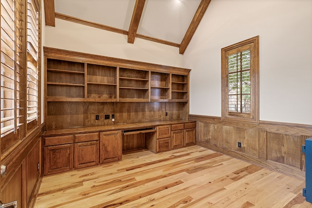 unfurnished office with built in desk, wooden walls, light wood-type flooring, and vaulted ceiling with beams